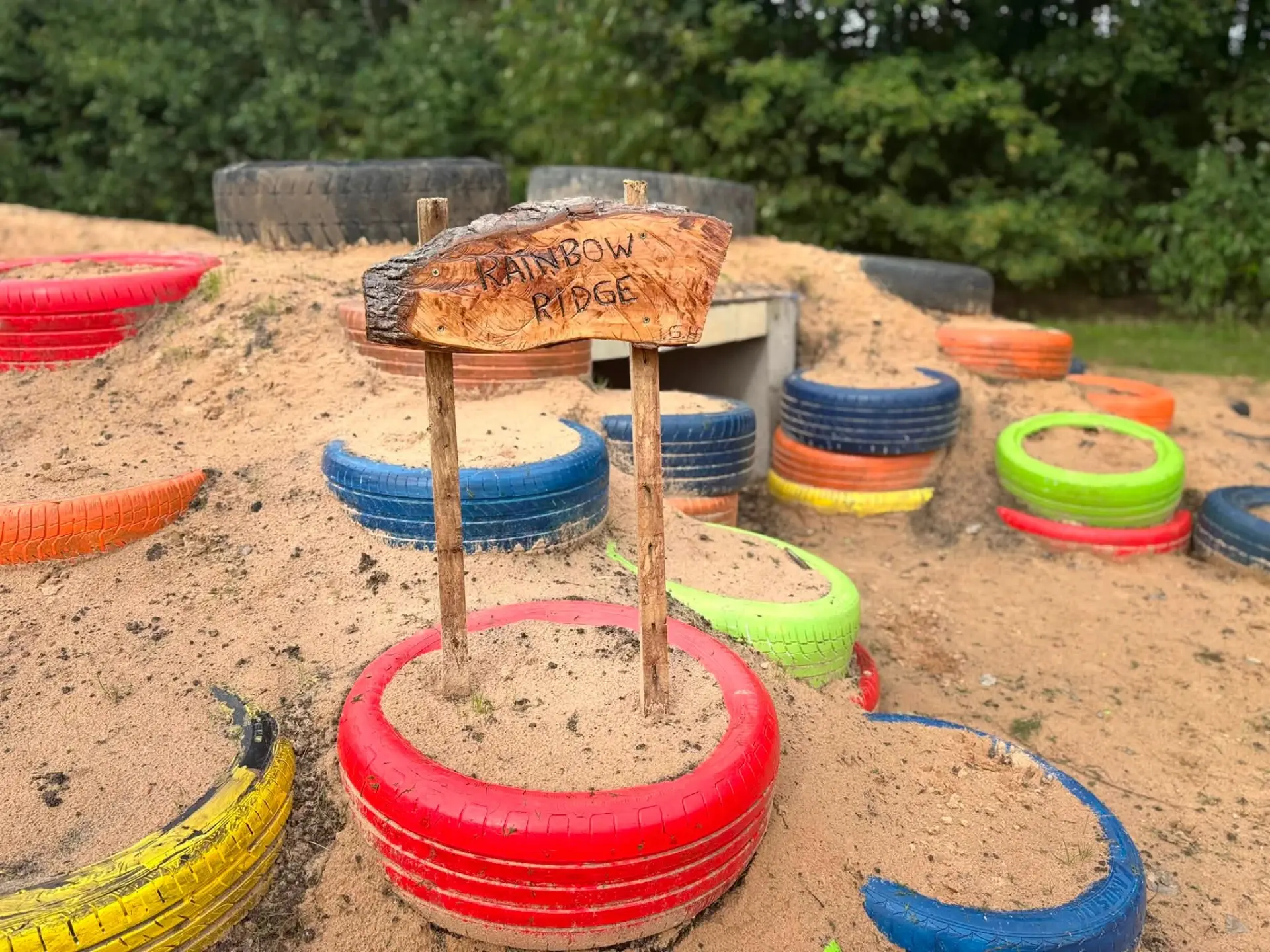 Rainbow Ridge sign set in a red tyre among colourful tyres