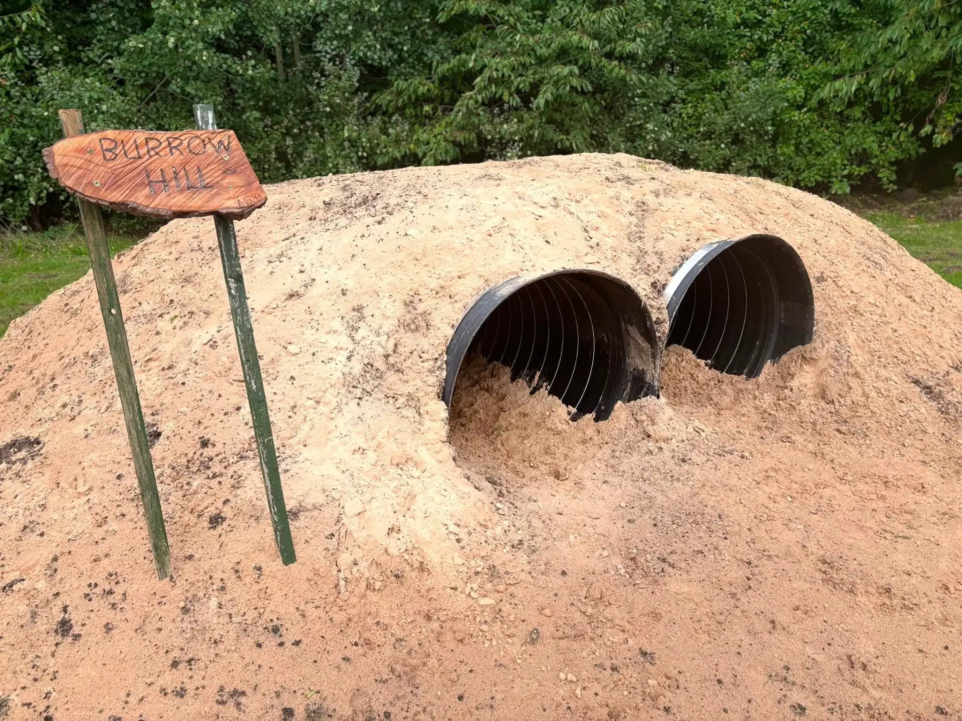 Carved Burrow Hill sign beside the tunnel mound