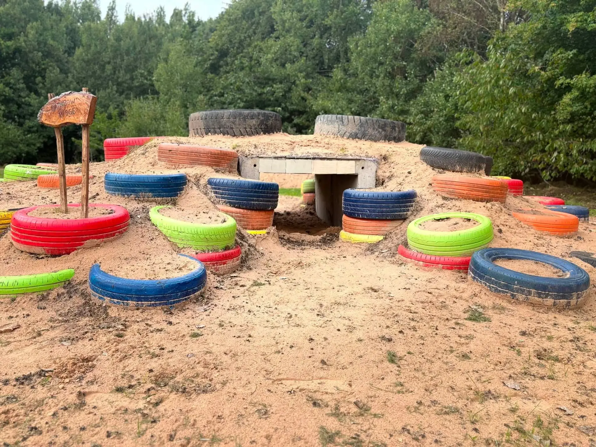Rainbow Ridge with brightly painted tyres set into the sand mound and a tunnel entrance