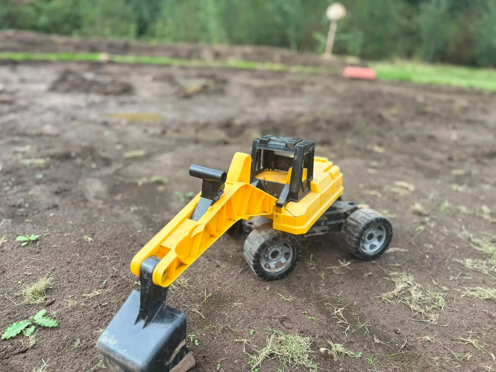 Toy digger on the freshly prepared play area soil